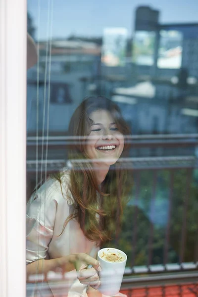 Mulher sorridente perto da janela — Fotografia de Stock