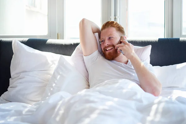 Man with phone in bed — Stock Photo, Image