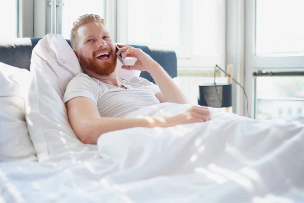 Man with phone in bed — Stock Photo, Image