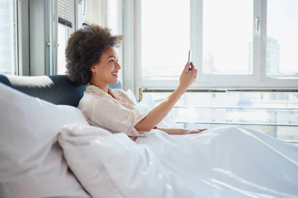 Žena používající audiovizuální volání v posteli — Stock fotografie