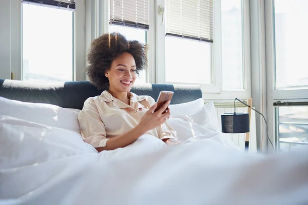 Junge Frau SMS im Bett — Stockfoto