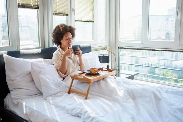 Женщина пьет утренний кофе в постели — стоковое фото
