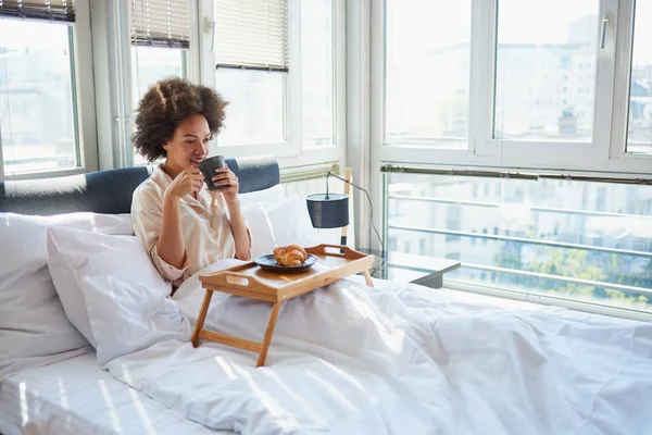 Женщина пьет утренний кофе в постели — стоковое фото