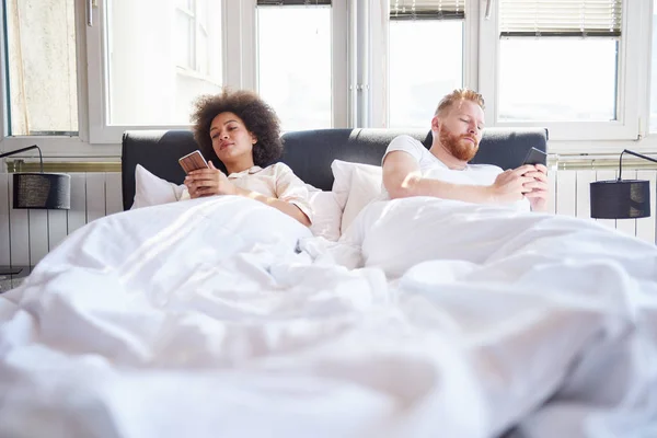 Paar benutzt Mobiltelefone im Bett — Stockfoto