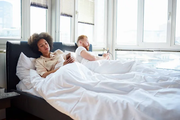 Pareja usando teléfonos móviles en la cama —  Fotos de Stock