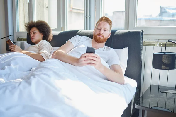 Paar benutzt Mobiltelefone im Bett — Stockfoto