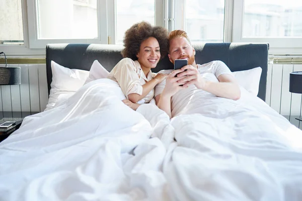 Paar schaut sich Handy-Video im Bett an — Stockfoto