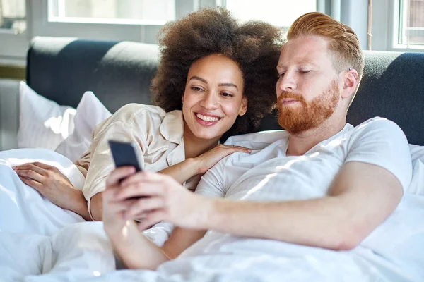 Couple regarder la vidéo sur le téléphone dans le lit — Photo