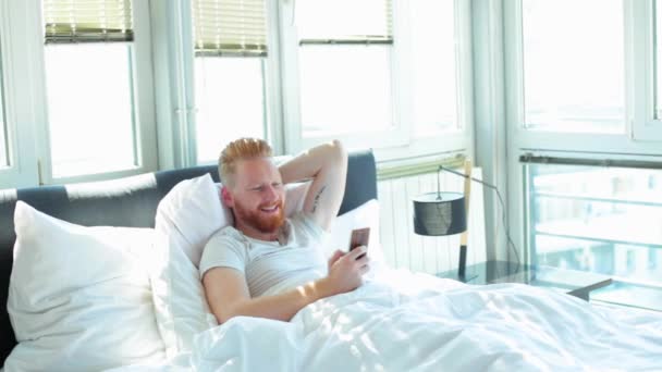 Людина використовує телефон в ліжку — стокове відео