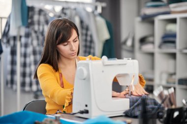 Stüdyosunda oturup güzel bir gece elbisesi dikmeye odaklanmış beyaz bir moda tasarımcısı..