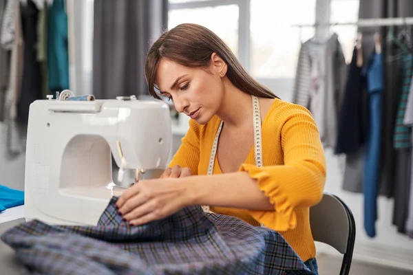 Focalisé charmant créateur de mode caucasien assis dans son studio et couture belle robe de soirée . — Photo