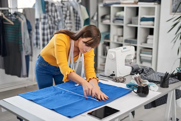 Tejidos de corte de costurera atractivos enfocados para hermoso vestido de noche mientras está de pie en su estudio . —  Fotos de Stock