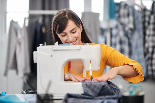 Enfocado encantador diseñador de moda caucásico sentado en su estudio y costura hermoso vestido de noche . —  Fotos de Stock