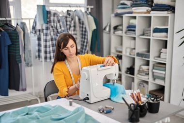 Stüdyosunda oturup güzel bir gece elbisesi dikmeye odaklanmış beyaz bir moda tasarımcısı..