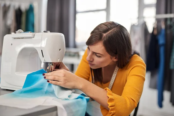 Enfocado encantador diseñador de moda caucásico sentado en su estudio y costura hermoso vestido de noche . —  Fotos de Stock