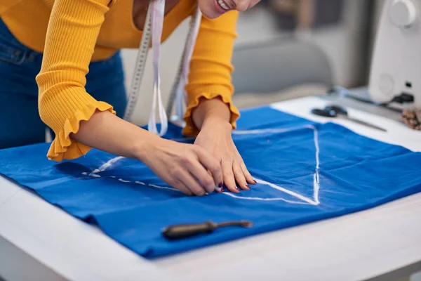 Criativa designer de moda caucasiano de pé em seu estúdio e esquema de desenho em linho azul para um belo vestido de noite . — Fotografia de Stock