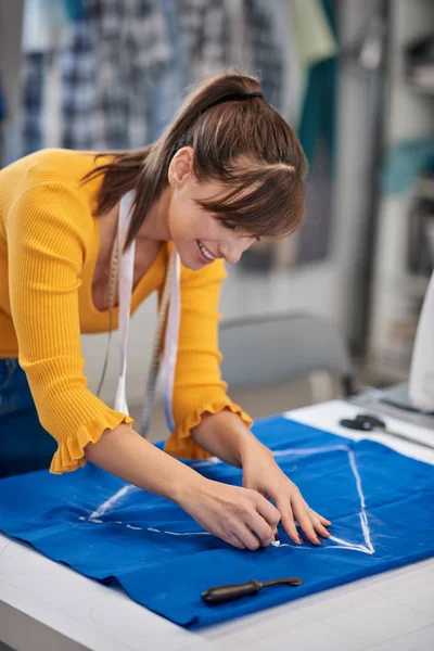 富有创意的高加索时装设计师站在工作室里，在蓝色亚麻布上为漂亮的睡衣作画. — 图库照片