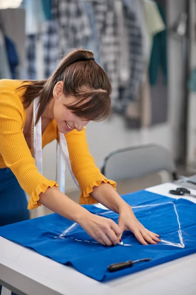 Творческий кавказский модельер стоит в своей студии и рисует схему на синем белье для красивого ночного платья . — стоковое фото