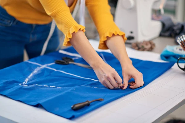 Criativa designer de moda caucasiano de pé em seu estúdio e esquema de desenho em linho azul para um belo vestido de noite . — Fotografia de Stock