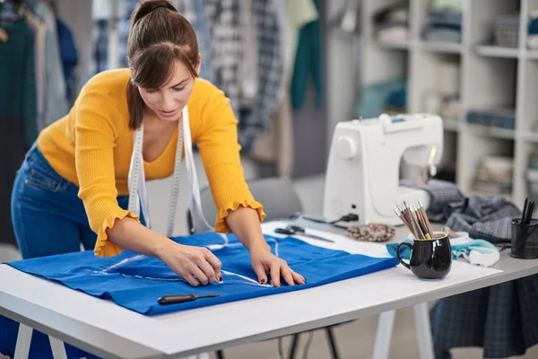 Creatieve Kaukasische mode-ontwerper staan in haar studio en tekening schema op blauw linnen voor een mooie nacht jurk. — Stockfoto