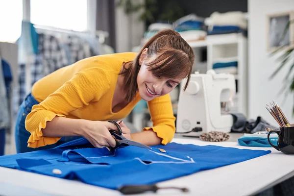 Couturière dédiée debout à côté de la table et des textiles de coupe pour une robe élégante . — Photo