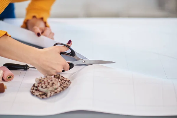 Close-up van vrouwelijke tailor snijden naad patroon voor kleding. — Stockfoto