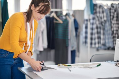 Kadın terzi giysiler için dikiş desenleri kesiyor..