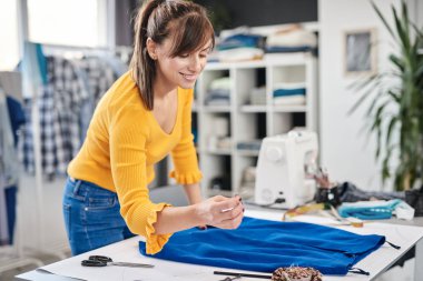 Odaklanmış güzel beyaz kadın dikiş iğnesi takıyor ve güzel etek yapıyor..