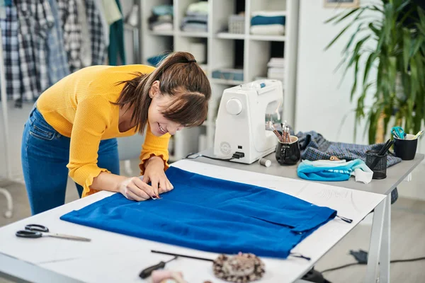 Encantador caucásico sonriente costura dedicada costura de dibujo costura con tiza en una falda . —  Fotos de Stock