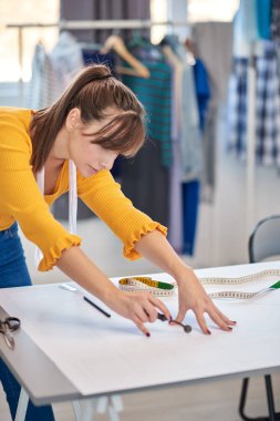 Kendini Kafkas terzisine adamış. Döner kesiciyle dikiş desenini kesiyor..