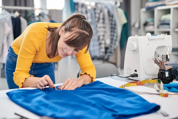 Encantador caucásico sonriente costura dedicada costura de dibujo costura con tiza en una falda . —  Fotos de Stock