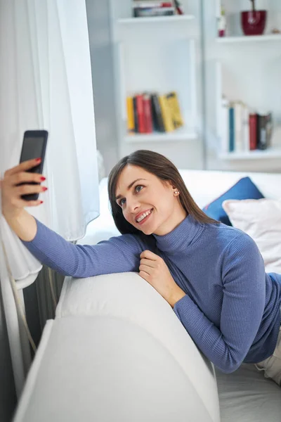 Junge attraktive lächelnde Brünette beim Selfie. Sie wird es in den sozialen Medien posten. — Stockfoto