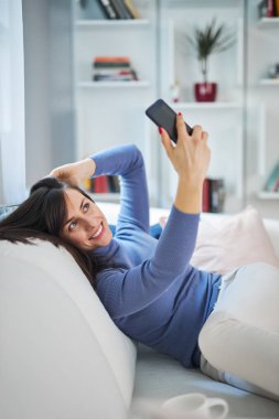 Çekici, gülümseyen esmer kız selfie çekiyor. Sosyal medyada yayınlayacak..