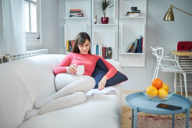 Genç, çekici, gülümseyen esmer kız evde dinleniyor..