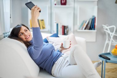 Çekici, gülümseyen esmer kız selfie çekiyor. Sosyal medyada yayınlayacak..