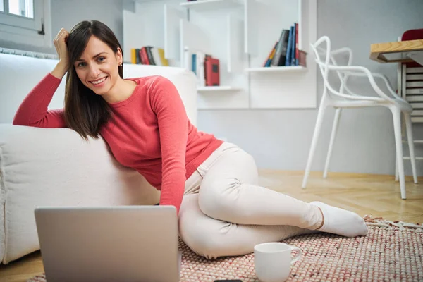年轻迷人的微笑女人坐在家里的地板上 用笔记本电脑 — 图库照片