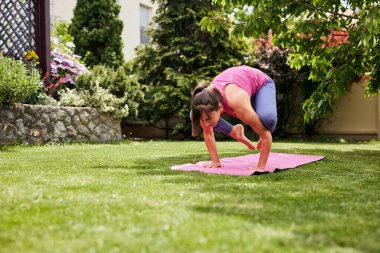 Turna yoga poziyonunda genç ve güçlü bir Yogi esmer. Arka bahçe dış tarafı..