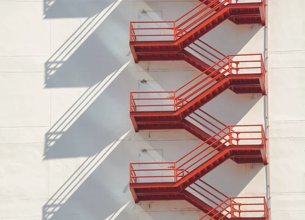 Red fire escape ladders on white building