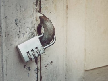 Eski asma kilit yeri ile ahşap kapı, anahtar kodu içeren metin. 