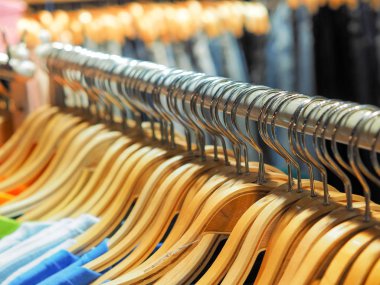Birçok ahşap elbise dolabında asılı ya da mağazada satılık elbise askısı var. Bir butik dükkanında şık kıyafetler..
