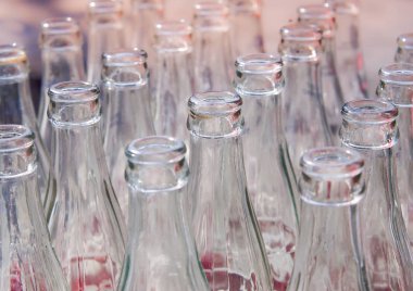 Sırayla dizilmiş birçok kullanılmış cam şişe. Boş soda şişelerinin yakın ve seçici odak noktası, geri dönüşümlü nesne resmi.