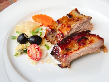 BBQ soslu ızgara domuz pirzolası ve balda karamelize edilmiş beyaz tabakta servis edilen meze. Barbekü kaburgalarını bbq sosuyla kapayın..