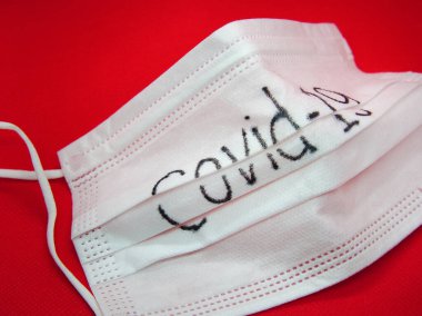 Corona virüsü Covid-19, kırmızı arka planda tıbbi maskeye yakın çekim. 