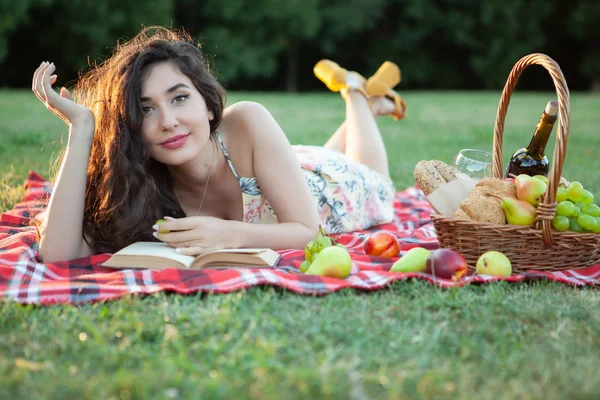 Sexy brunetka žena na piknik deka v parku. — Stock fotografie