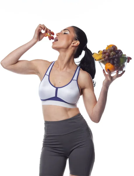 Seksowna Brunetka Stroju Fitness Jedząca Owoce Studio Strzelać Izolowane Białym — Zdjęcie stockowe