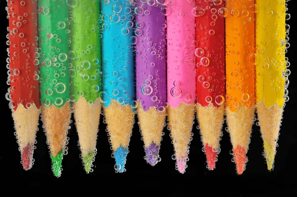 Lápices de colores de cerca en el agua con burbujas — Foto de Stock