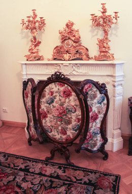 Şömine ile altın bir saat ve şamdanlar.