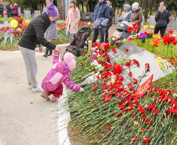 Çiçekler için bir anıt tabak koyarak bir çocuk.