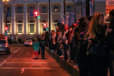 Kaldırımda gösterinin başlangıcını bekleyen insanlar var..
