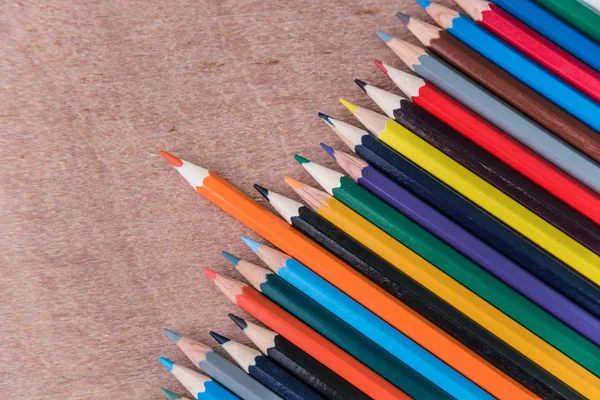 Muitos lápis de cor no fundo de madeira marrom — Fotografia de Stock